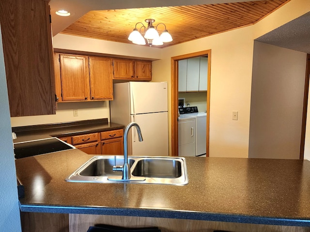520 5th St SW Unit 318, Willmar, MN 56201 - kitchen featuring washing machine and dryer, freestanding refrigerator, a sink, dark countertops, and brown cabinets