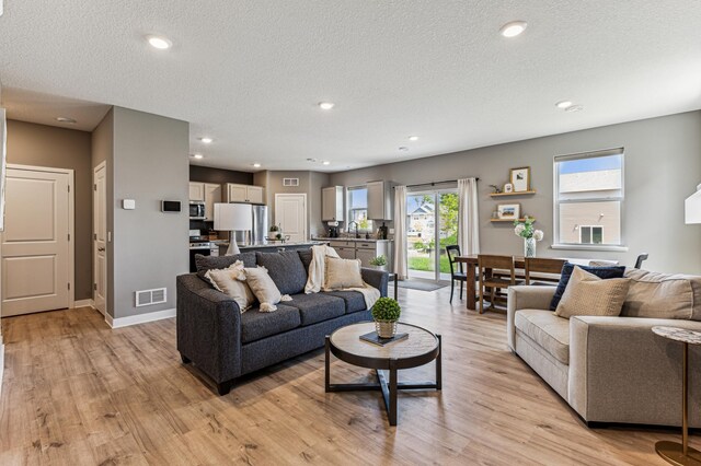 12719 Erskin St NE, Blaine, MN 55449 - living room featuring light wood-style floors, a textured ceiling, recessed lighting, and baseboards