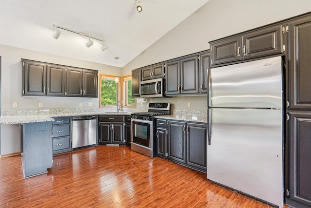 1504 Monarch St, Shakopee, MN 55379 - kitchen featuring appliances with stainless steel finishes, light stone counters, lofted ceiling, dark wood-type flooring, and track lighting