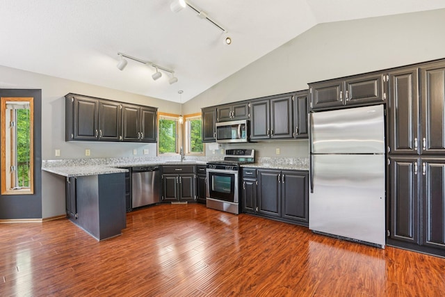 1504 Monarch St, Shakopee, MN 55379 - kitchen with appliances with stainless steel finishes, lofted ceiling, light stone counters, rail lighting, and dark wood-type flooring