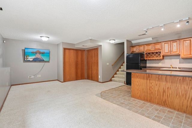 1504 Monarch St, Shakopee, MN 55379 - kitchen featuring freestanding refrigerator, open floor plan, a textured ceiling, light colored carpet, and dark countertops