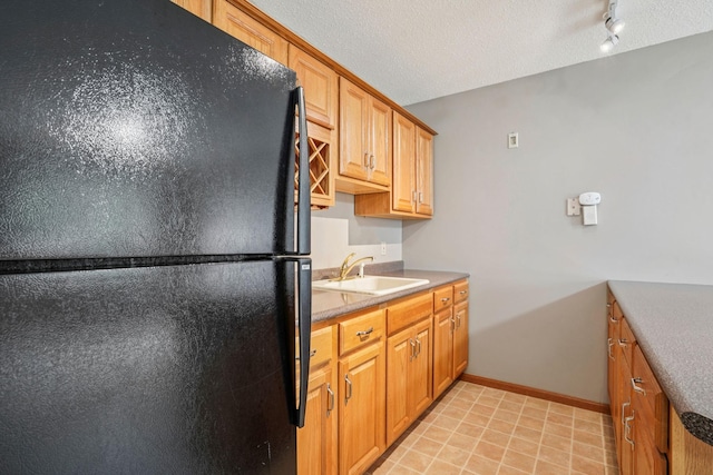 1504 Monarch St, Shakopee, MN 55379 - kitchen with freestanding refrigerator, a textured ceiling, and brown cabinetry