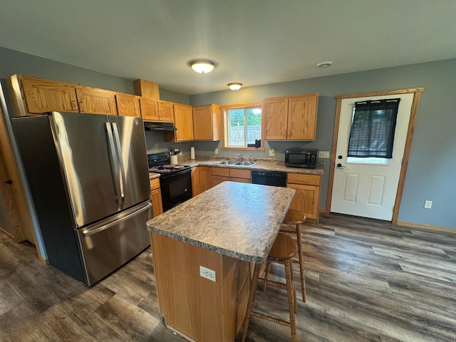1101 Timbers Dr, Park Rapids, MN 56470 - kitchen with black appliances, a sink, a breakfast bar area, under cabinet range hood, and dark wood-style floors
