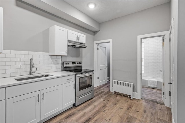 608 Beaumont St, Saint Paul, MN 55130 - kitchen with radiator, a sink, electric stove, under cabinet range hood, and white cabinetry