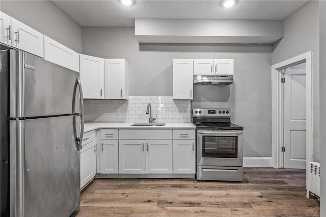 608 Beaumont St, Saint Paul, MN 55130 - kitchen featuring stainless steel appliances, a sink, under cabinet range hood, radiator heating unit, and white cabinetry