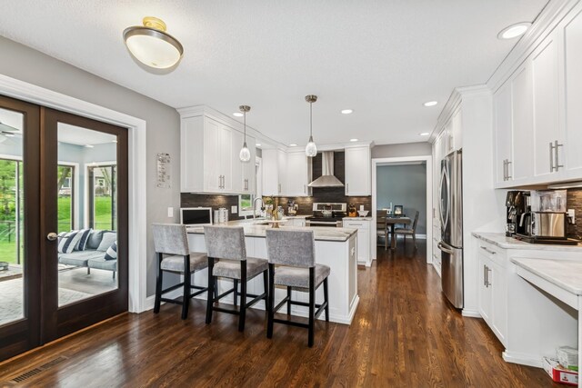 3720 Ximines Ln N, Plymouth, MN 55441 - kitchen featuring wall chimney range hood, stainless steel appliances, french doors, tasteful backsplash, and white cabinetry