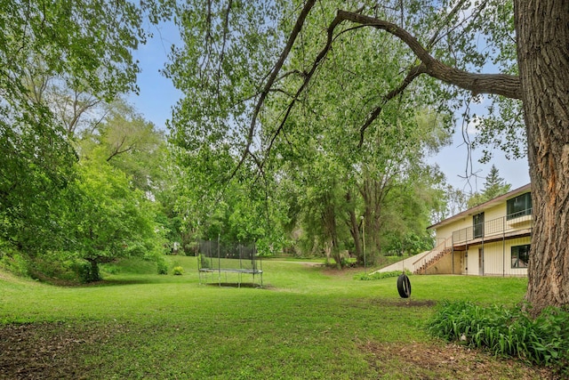 2065 124th Ln NW, Coon Rapids, MN 55448 - view of green lawn with a trampoline, stairway, and a deck