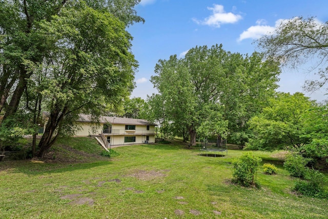 2065 124th Ln NW, Coon Rapids, MN 55448 - view of grassy yard featuring a trampoline, stairs, and a deck