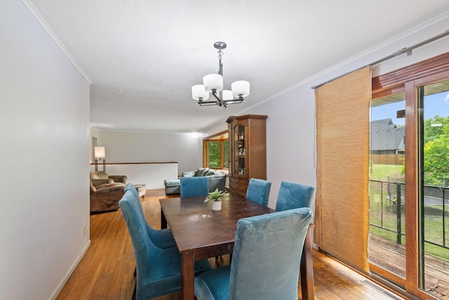 2065 124th Ln NW, Coon Rapids, MN 55448 - dining space with ornamental molding, a chandelier, plenty of natural light, and wood finished floors