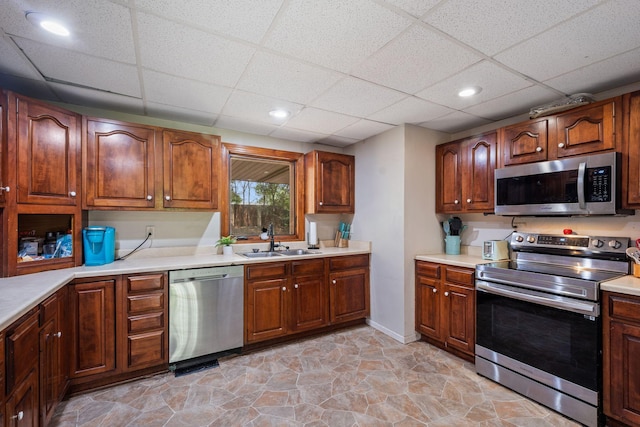 2065 124th Ln NW, Coon Rapids, MN 55448 - kitchen with appliances with stainless steel finishes, a sink, a paneled ceiling, light countertops, and baseboards