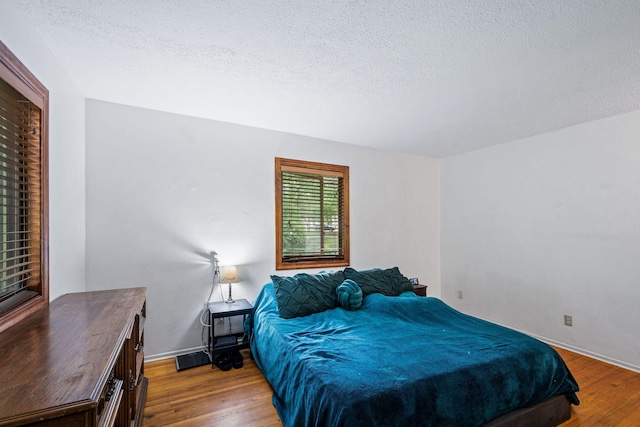 2065 124th Ln NW, Coon Rapids, MN 55448 - bedroom featuring wood finished floors, a textured ceiling, and baseboards