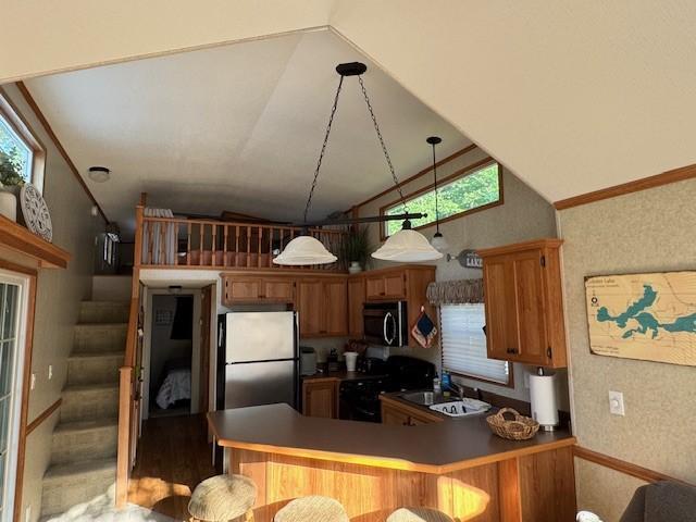2221 Reubens Ln SW Unit 20, Farwell, MN 56327 - kitchen featuring appliances with stainless steel finishes, lofted ceiling, a peninsula, brown cabinets, and plenty of natural light