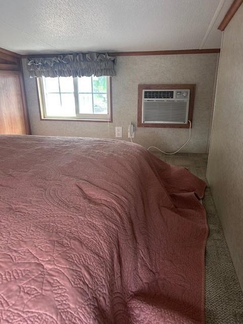2221 Reubens Ln SW Unit 20, Farwell, MN 56327 - carpeted bedroom with ornamental molding, a textured ceiling, and a wall mounted air conditioner