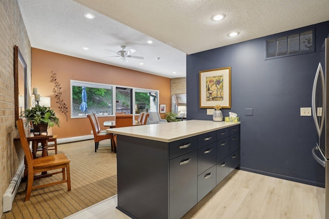 5697 Green Circle Dr Unit 216, Minnetonka, MN 55343 - kitchen featuring a peninsula, stainless steel refrigerator, a textured ceiling, a ceiling fan, and light countertops