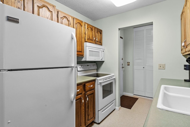183 Little Canada Rd E Unit 310, Little Canada, MN 55117 - kitchen featuring white appliances, light countertops, brown cabinets, a textured ceiling, and baseboards