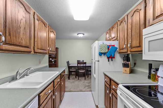 183 Little Canada Rd E Unit 310, Little Canada, MN 55117 - kitchen featuring a sink, white appliances, light colored carpet, brown cabinets, and a textured ceiling