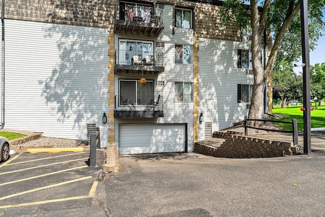 183 Little Canada Rd E Unit 310, Little Canada, MN 55117 - view of property exterior with mansard roof, an attached garage, and a balcony