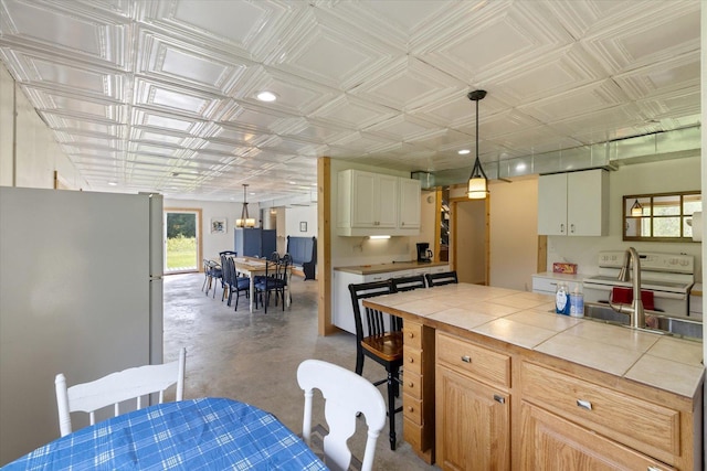 11556 Blackwood Rd, Floodwood Twp, MN 55736 - kitchen featuring white appliances, finished concrete flooring, tile counters, an ornate ceiling, and hanging light fixtures