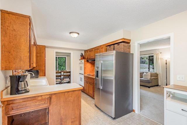 2205 Valders Ave N, Golden Valley, MN 55427 - kitchen with stainless steel fridge with ice dispenser, brown cabinetry, plenty of natural light, and a textured ceiling