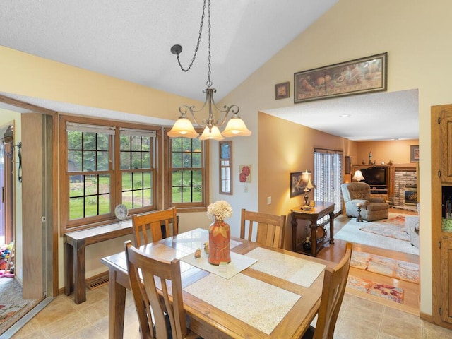 9160 164th Ln NW, Ramsey, MN 55303 - dining space featuring a chandelier, a fireplace with raised hearth, a textured ceiling, and high vaulted ceiling