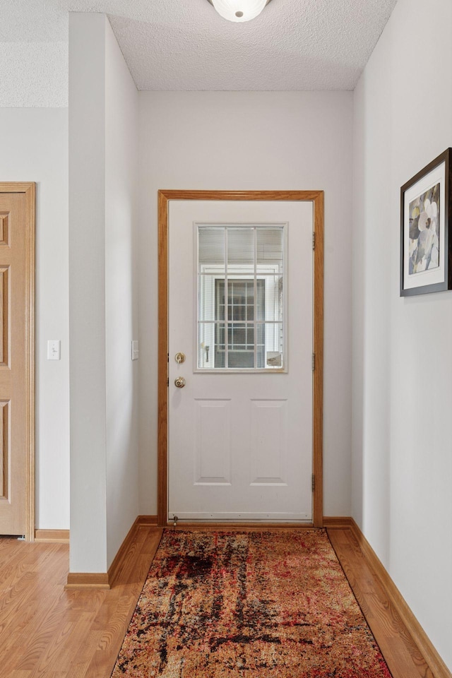1848 111th Ave NE, Blaine, MN 55449 - doorway to outside featuring light wood-style floors, a textured ceiling, and baseboards