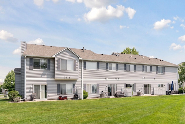 1848 111th Ave NE, Blaine, MN 55449 - back of house featuring a lawn, central AC unit, a chimney, and roof with shingles
