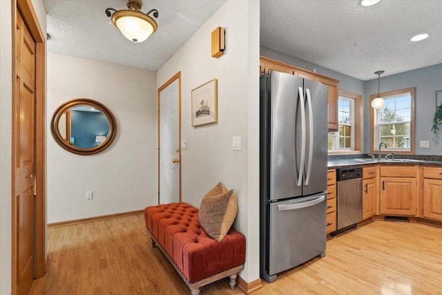 1107 Golden Way NW, Isanti, MN 55040 - kitchen featuring appliances with stainless steel finishes, a sink, a textured ceiling, light wood-style flooring, and dark countertops