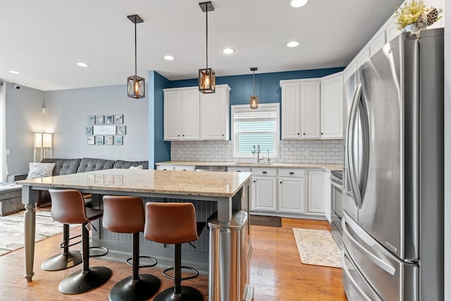 11230 68th St NE, Albertville, MN 55301 - kitchen with stainless steel appliances, open floor plan, a kitchen bar, backsplash, and recessed lighting