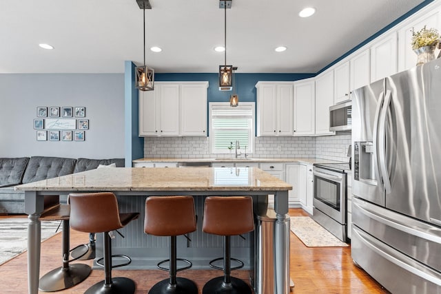 11230 68th St NE, Albertville, MN 55301 - kitchen with appliances with stainless steel finishes, a breakfast bar area, backsplash, white cabinetry, and recessed lighting