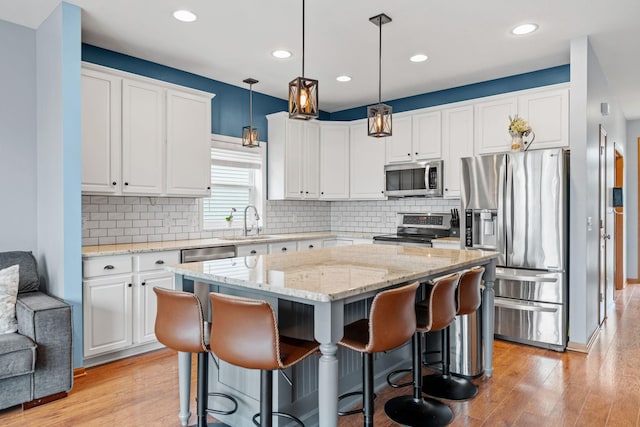 11230 68th St NE, Albertville, MN 55301 - kitchen with stainless steel appliances, white cabinetry, light wood finished floors, a kitchen island, and recessed lighting
