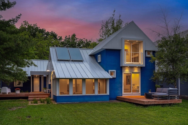 303 77th St, Chanhassen, MN 55317 - back of house at dusk featuring a standing seam roof, a deck, and a lawn