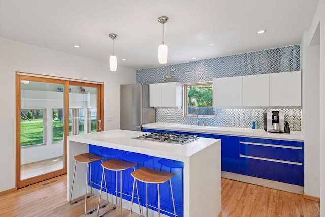 303 77th St, Chanhassen, MN 55317 - kitchen featuring a sink, stainless steel appliances, white cabinets, backsplash, and light wood-style floors