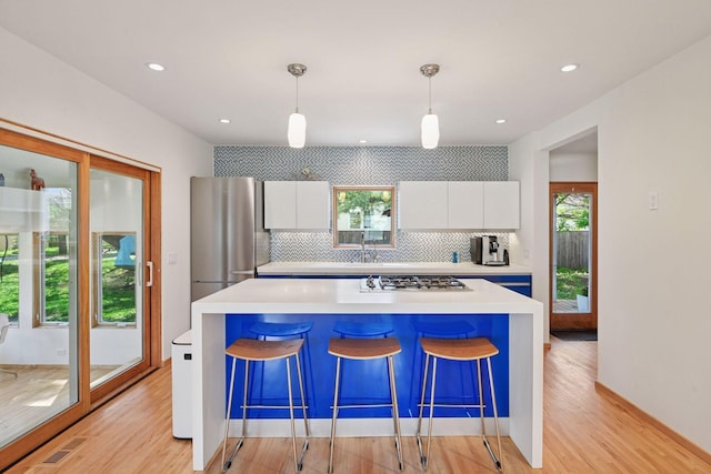 303 77th St, Chanhassen, MN 55317 - kitchen with stainless steel appliances, white cabinets, tasteful backsplash, light wood-style flooring, and recessed lighting