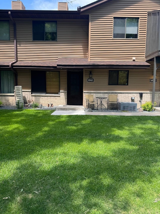 8942 Underwood Ln N, Maple Grove, MN 55369 - back of property with a chimney, a lawn, brick siding, and central AC