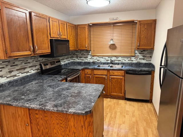 8942 Underwood Ln N, Maple Grove, MN 55369 - kitchen featuring appliances with stainless steel finishes, a sink, light wood-type flooring, brown cabinets, and a textured ceiling