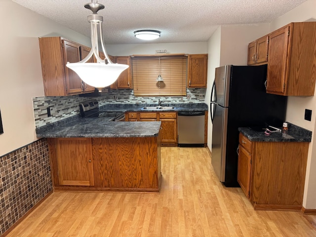 8942 Underwood Ln N, Maple Grove, MN 55369 - kitchen with stainless steel appliances, a peninsula, a sink, light wood finished floors, and a textured ceiling