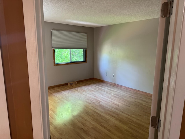 8942 Underwood Ln N, Maple Grove, MN 55369 - unfurnished room featuring wood finished floors, a textured ceiling, and baseboards
