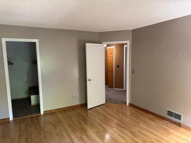 8942 Underwood Ln N, Maple Grove, MN 55369 - unfurnished bedroom featuring light wood finished floors, a textured ceiling, baseboards, and a closet