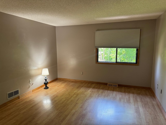 8942 Underwood Ln N, Maple Grove, MN 55369 - spare room with wood finished floors, a textured ceiling, and baseboards
