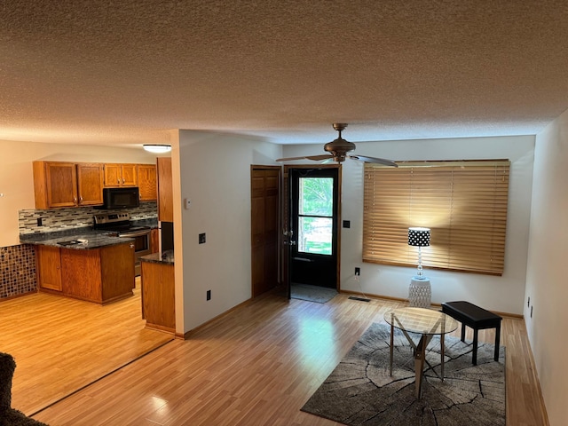 8942 Underwood Ln N, Maple Grove, MN 55369 - kitchen with stainless steel range with electric stovetop, black microwave, brown cabinetry, light wood-type flooring, and dark countertops