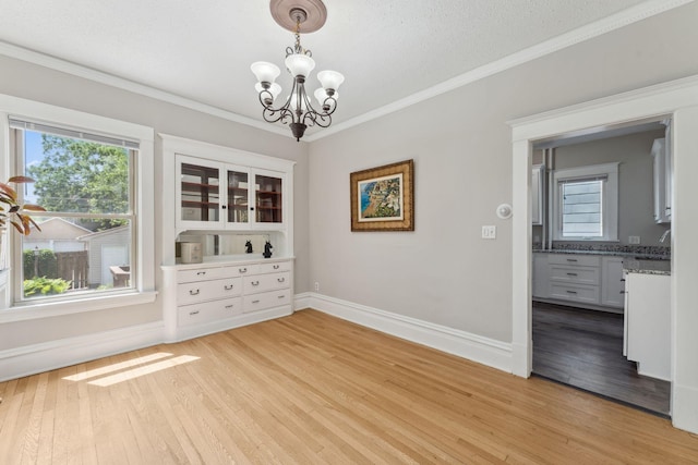 1744 Marshall Ave, Saint Paul, MN 55104 - empty room with a chandelier, light wood-style flooring, crown molding, plenty of natural light, and baseboards
