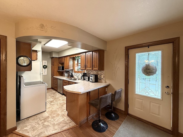 288 Locust St, Dawson, MN 56232 - kitchen with washer / clothes dryer, appliances with stainless steel finishes, arched walkways, a peninsula, and light countertops