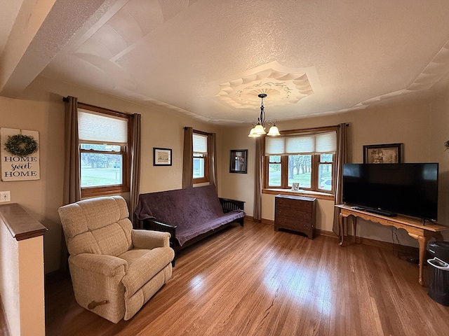 288 Locust St, Dawson, MN 56232 - living room featuring wood finished floors, baseboards, a textured ceiling, and a chandelier
