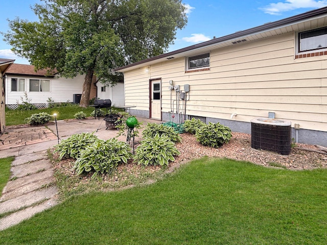 288 Locust St, Dawson, MN 56232 - rear view of property with cooling unit, a patio, and a lawn