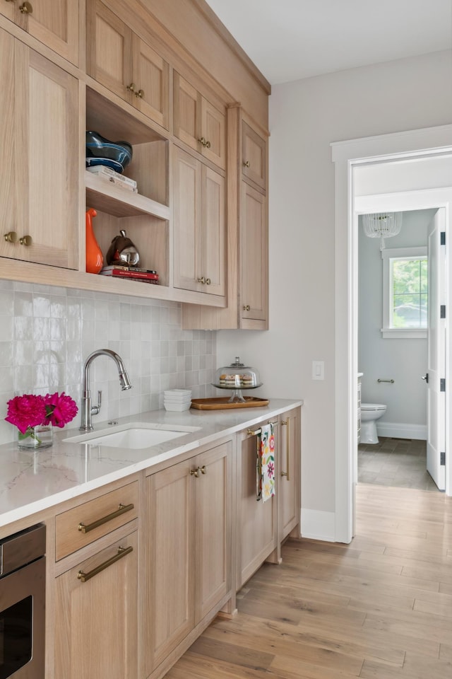 2475 Dunwoody Ave, Orono, MN 55391 - kitchen with a sink, light brown cabinets, decorative backsplash, light wood-style flooring, and light stone counters