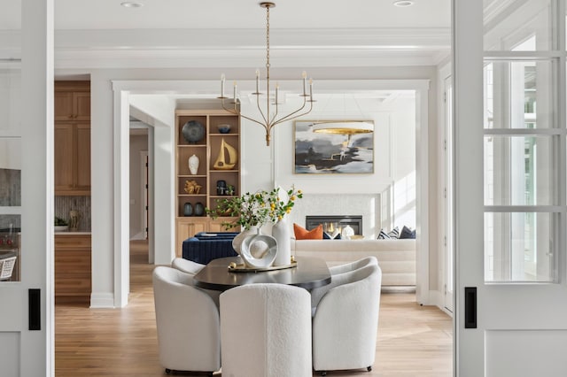 2475 Dunwoody Ave, Orono, MN 55391 - dining area featuring a chandelier, light wood-style flooring, ornamental molding, and a glass covered fireplace
