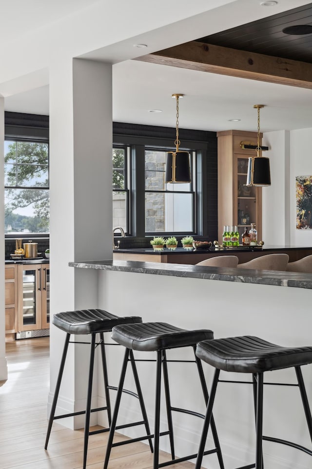 2475 Dunwoody Ave, Orono, MN 55391 - kitchen featuring healthy amount of natural light, beam ceiling, a breakfast bar, decorative light fixtures, and wine cooler