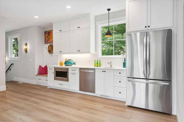 2475 Dunwoody Ave, Orono, MN 55391 - kitchen featuring appliances with stainless steel finishes, baseboards, white cabinets, decorative light fixtures, and light countertops