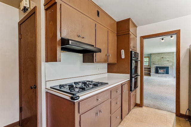 20257 Viking Blvd NE, Wyoming, MN 55092 - kitchen featuring under cabinet range hood, light countertops, baseboards, gas stovetop, and a stone fireplace