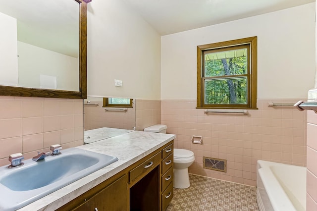 20257 Viking Blvd NE, Wyoming, MN 55092 - bathroom featuring tile walls, a wainscoted wall, vanity, toilet, and a tub to relax in